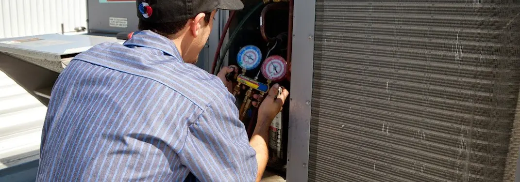 HVAC technician servicing a condenser unit in Mexia