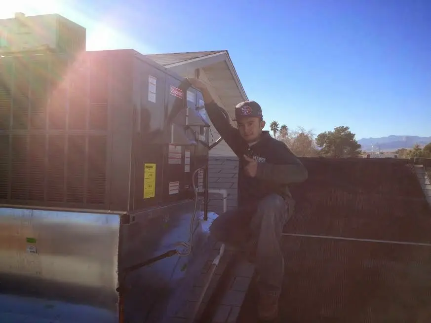HVAC technician performing Heat Pump Repair on a rooftop unit in Mexia